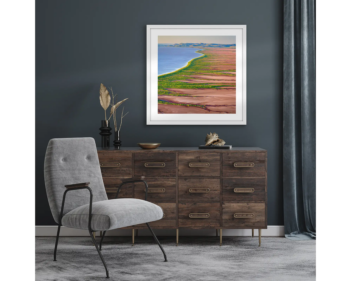 Lighting the Gulf. Wall art print with a white frame of sunset over Cambridge Gulf mudflats, The Kimberley, hung in a room with dark walls.
