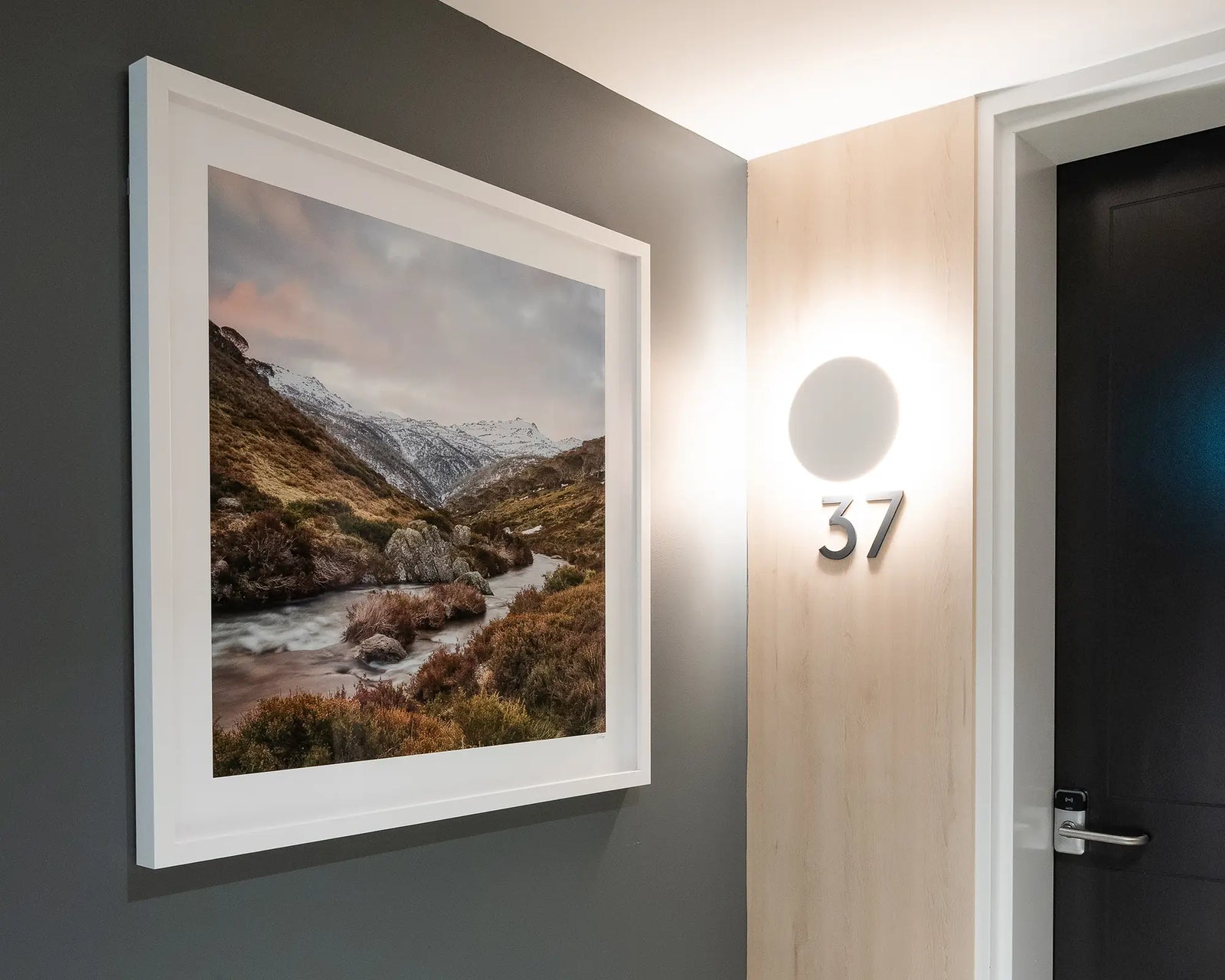 Framed wall art print of the Thredbo River flowing past heath and rocks with snow on Mount Kosciuszko in the background.