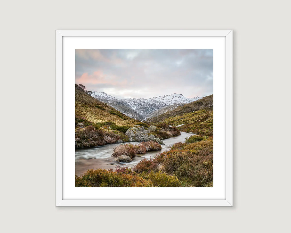 Framed wall art print of the Thredbo River flowing past heath and rocks with snow on Mount Kosciuszko in the background.