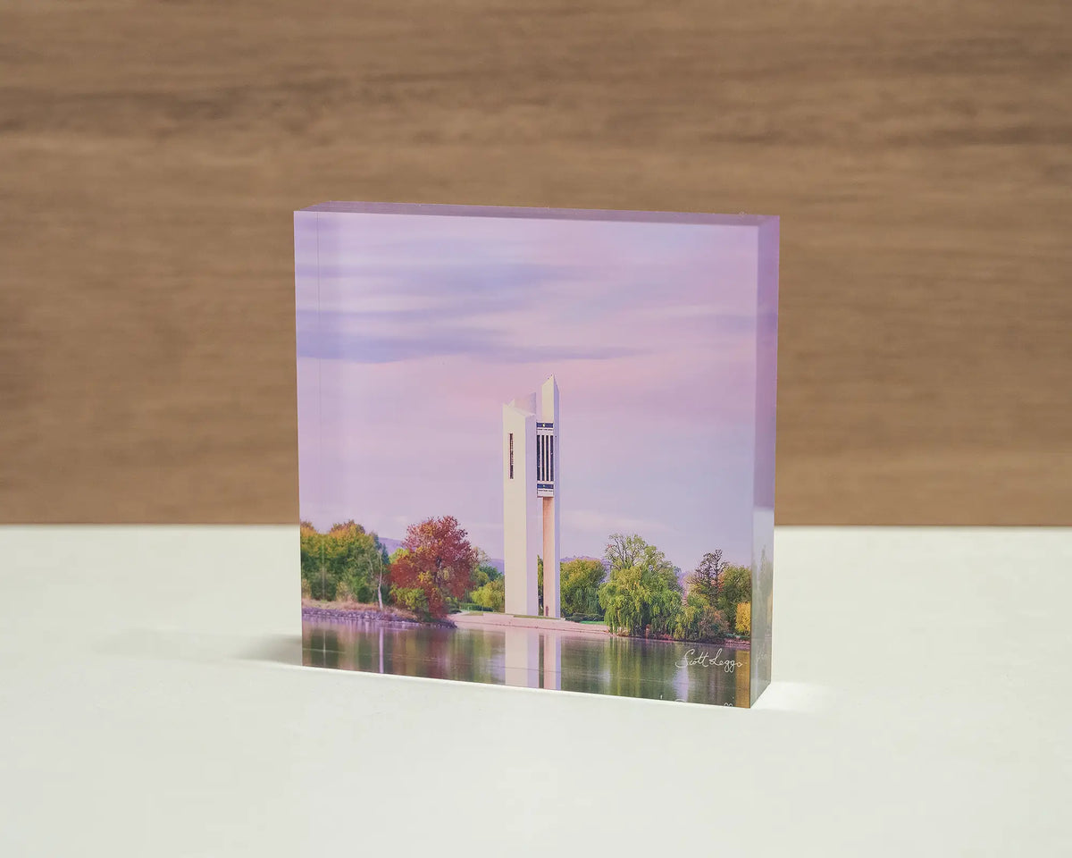 Magenta Dawn. Acrylic block of sunrise at the National Carillon Canberra, with an angled view sitting on a desk.