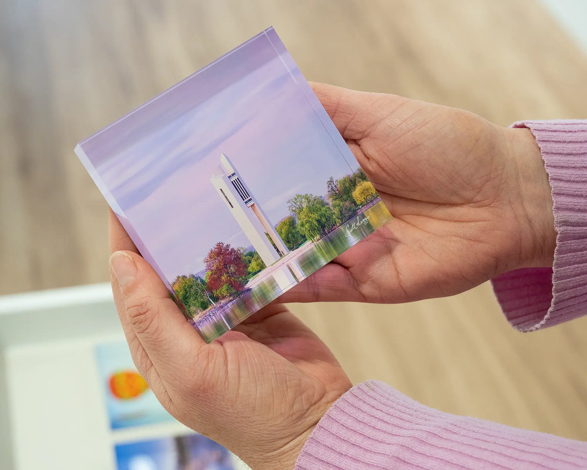 Magenta Dawn. Small acrylic block of sunrise at National Carillon Canberra, being held in hands.