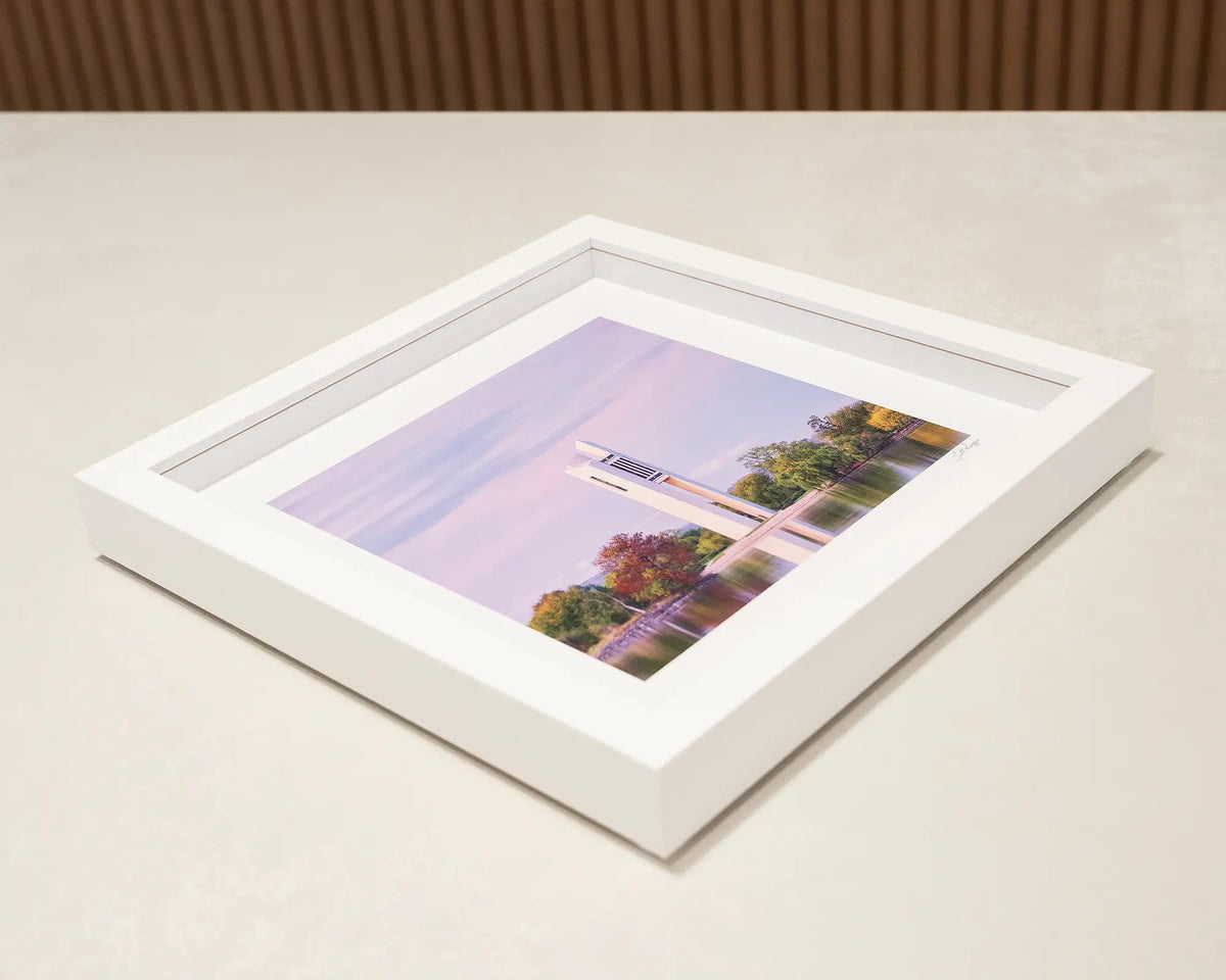 Magenta Dawn. Sunrise over the National Carillon Canberra, small framed print laying flat on a desk.