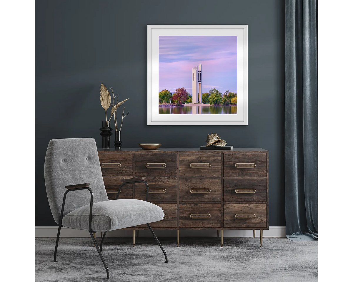 Magenta Dawn. Wall art print with white frame of National Carillon Canberra, at sunrise, hung in a room with dark walls.
