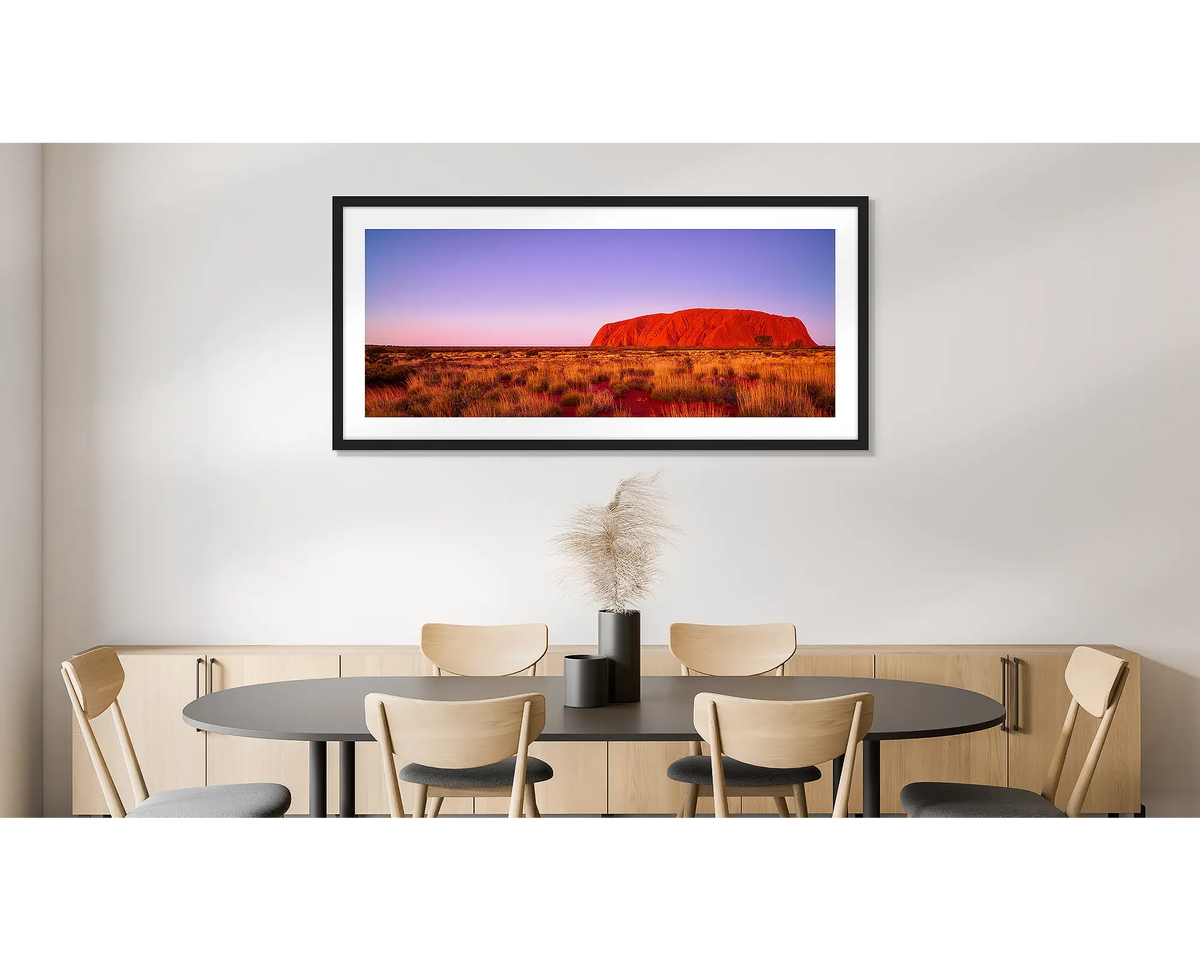 Majestic Uluru. Photographic wall art print of Uluru at sunset, framed in a black frame and hung on a dining room wall. 