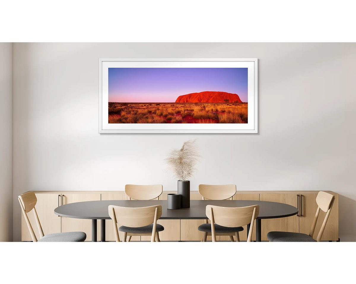 Majestic Uluru. Photographic wall art print of Uluru at sunset, framed in a white frame and hung on a dining room wall. 