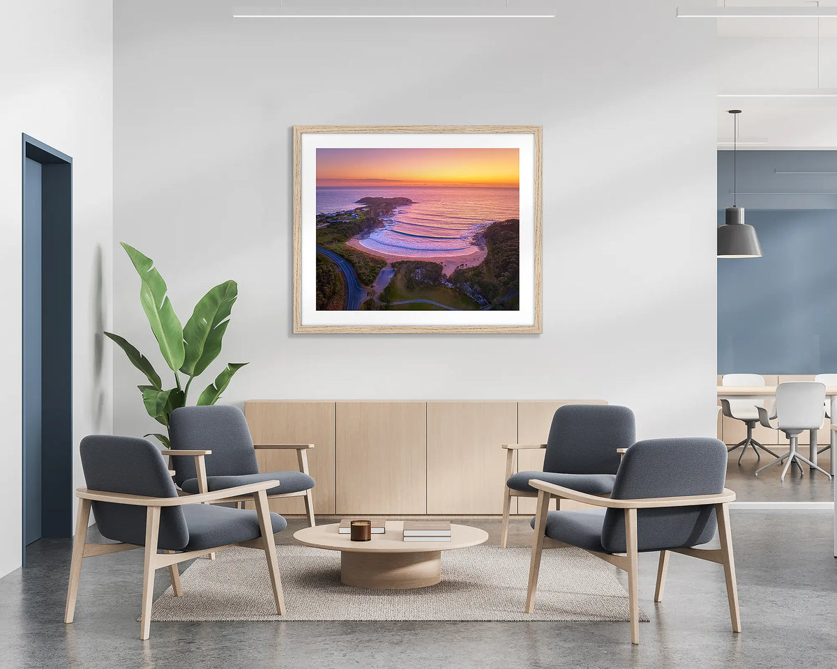 McKenzies Glow.  Wall art print of a sunrise over McKenzie&#39;s Beach, with a Tasmanian Oak frame, hung on the wall of a waiting area.