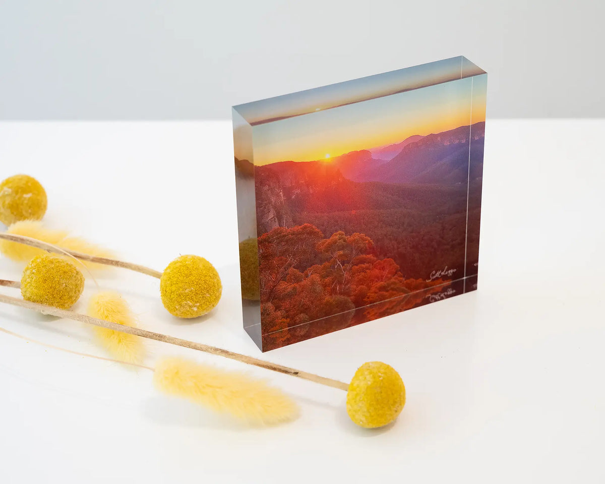 Moment In Time. Acrylic block of sun rising over Gross Valley, Blue Mountains National Park, styled on a desk with dried flowers.