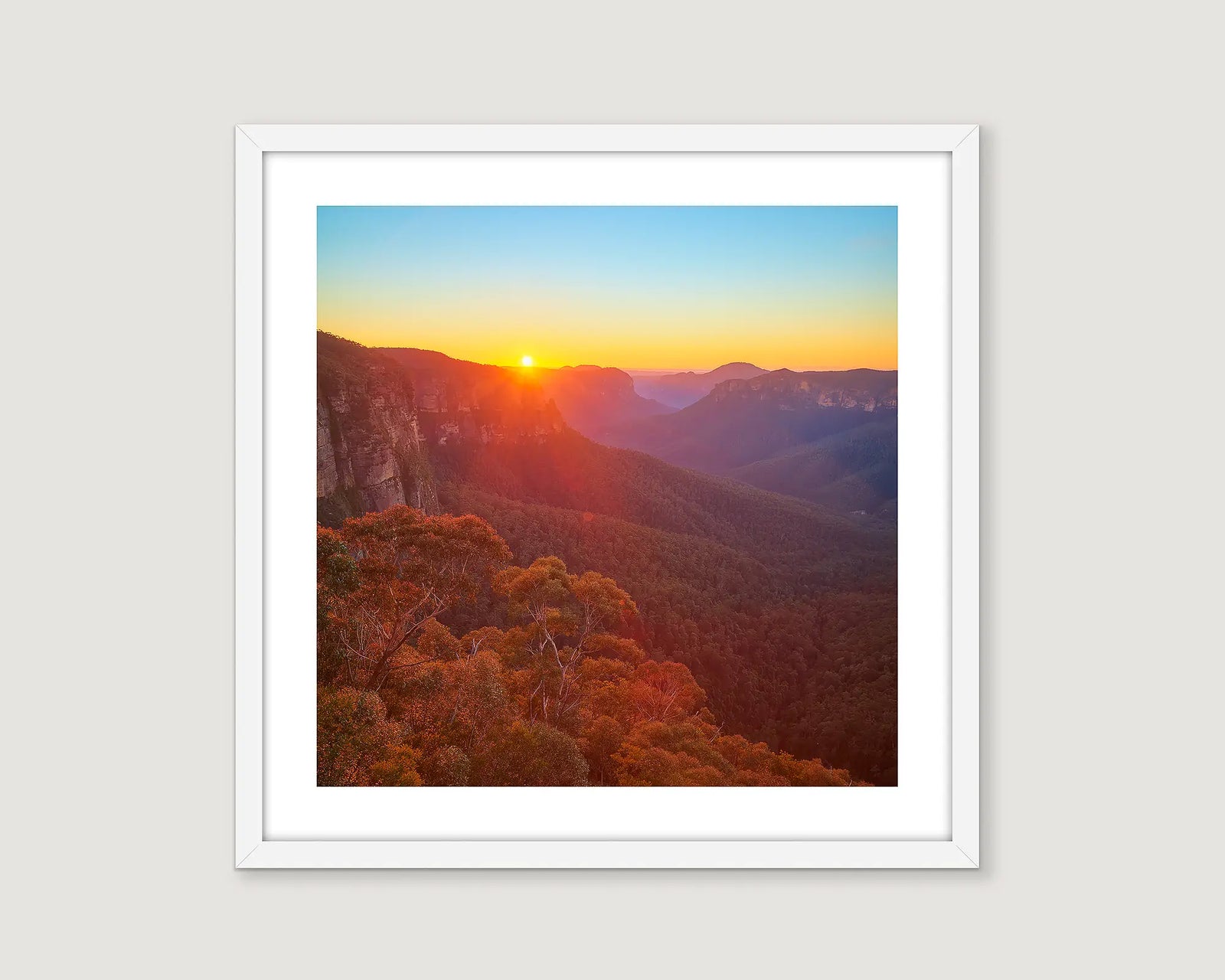 Framed photograph of a mountain region and a golden sunrise.
