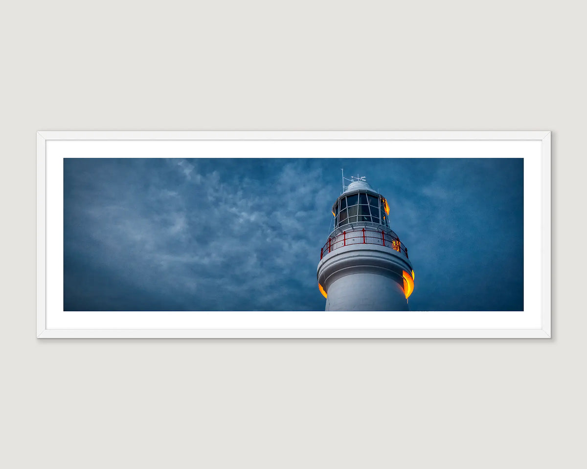 Framed photograph of a lighthouse at night against a stormy sky.