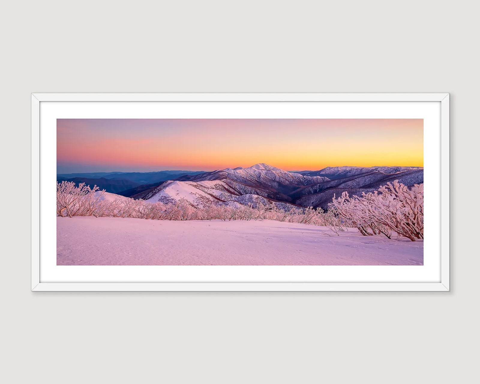 Framed photograph of a mountain range in snow at sunrise.