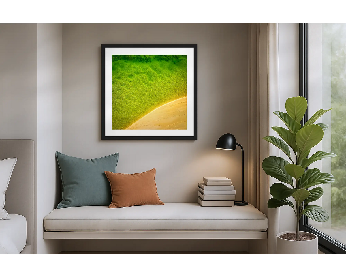 Mosaic. Aerial view of Durras Lake, wall art print in a black frame hung in an apartment bedroom. 