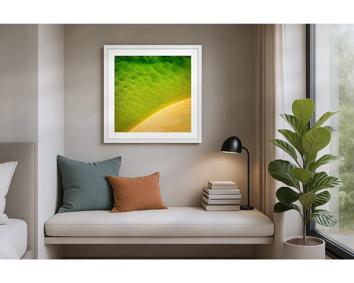 Mosaic. Aerial view of Durras Lake, wall art print in a white frame hung in an apartment bedroom. 