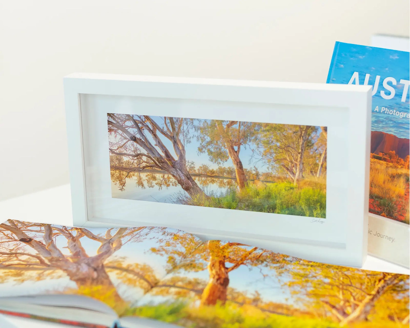 Framed landscape photograph of the Murray River with gum trees and a blue sky.