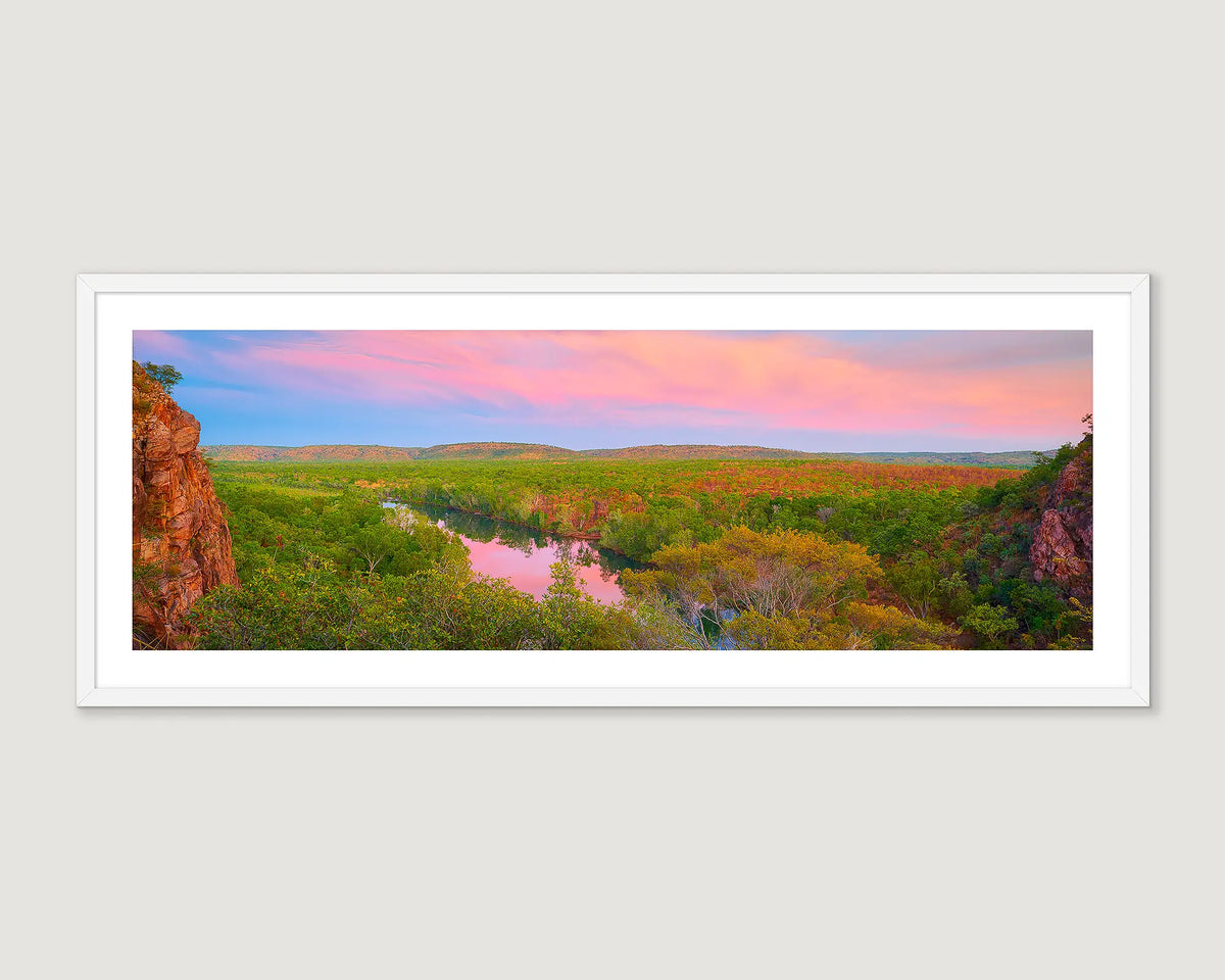Framed landscape photograph of a gorge surrounded by trees and a pink and blue sunrise.