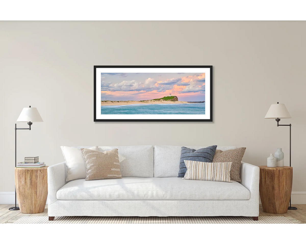 Newcastle Magic. Wall art print of a sunset over Nobby&#39;s Beach, Newcastle, framed with a black frame and hung above a couch. 