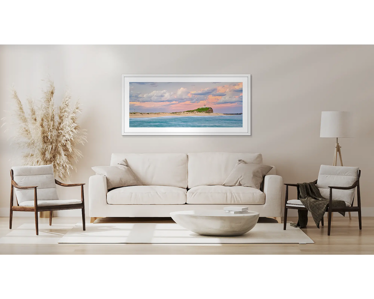 Newcastle Magic. Wall art print with a white frame of sunset over Nobby&#39;s Beach Newcastle, hung above a couch.
