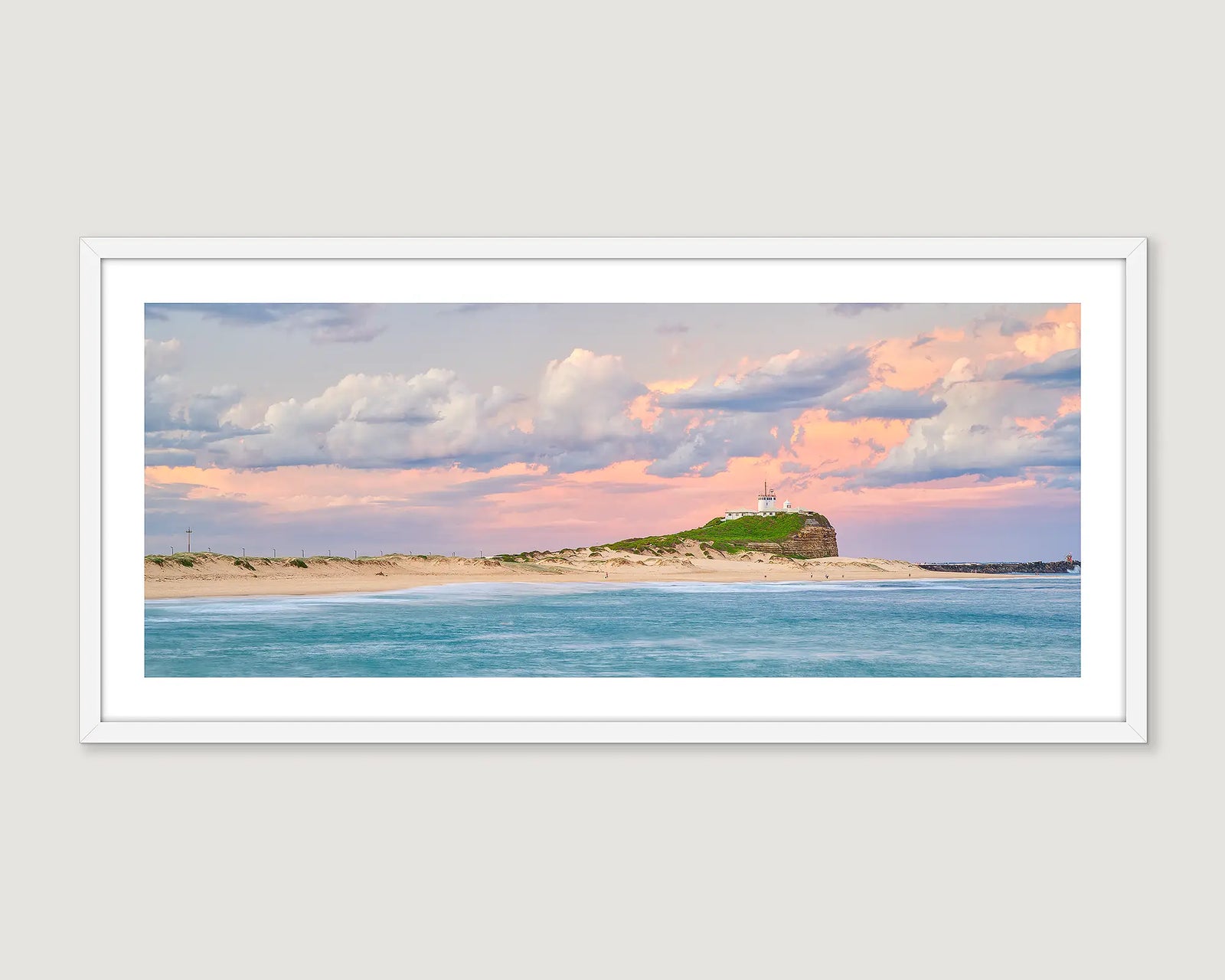 Framed landscape photograph of an ocean and sand and a pastel sunrise.