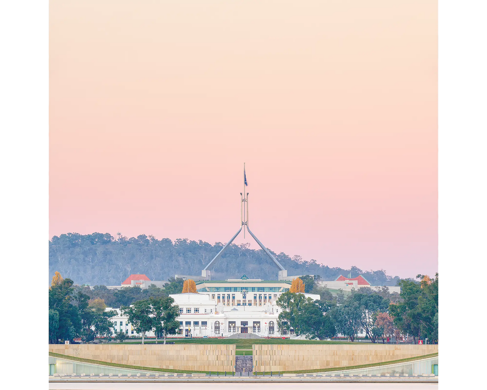 Old and New Parliament House Canberra with pink sunrise.