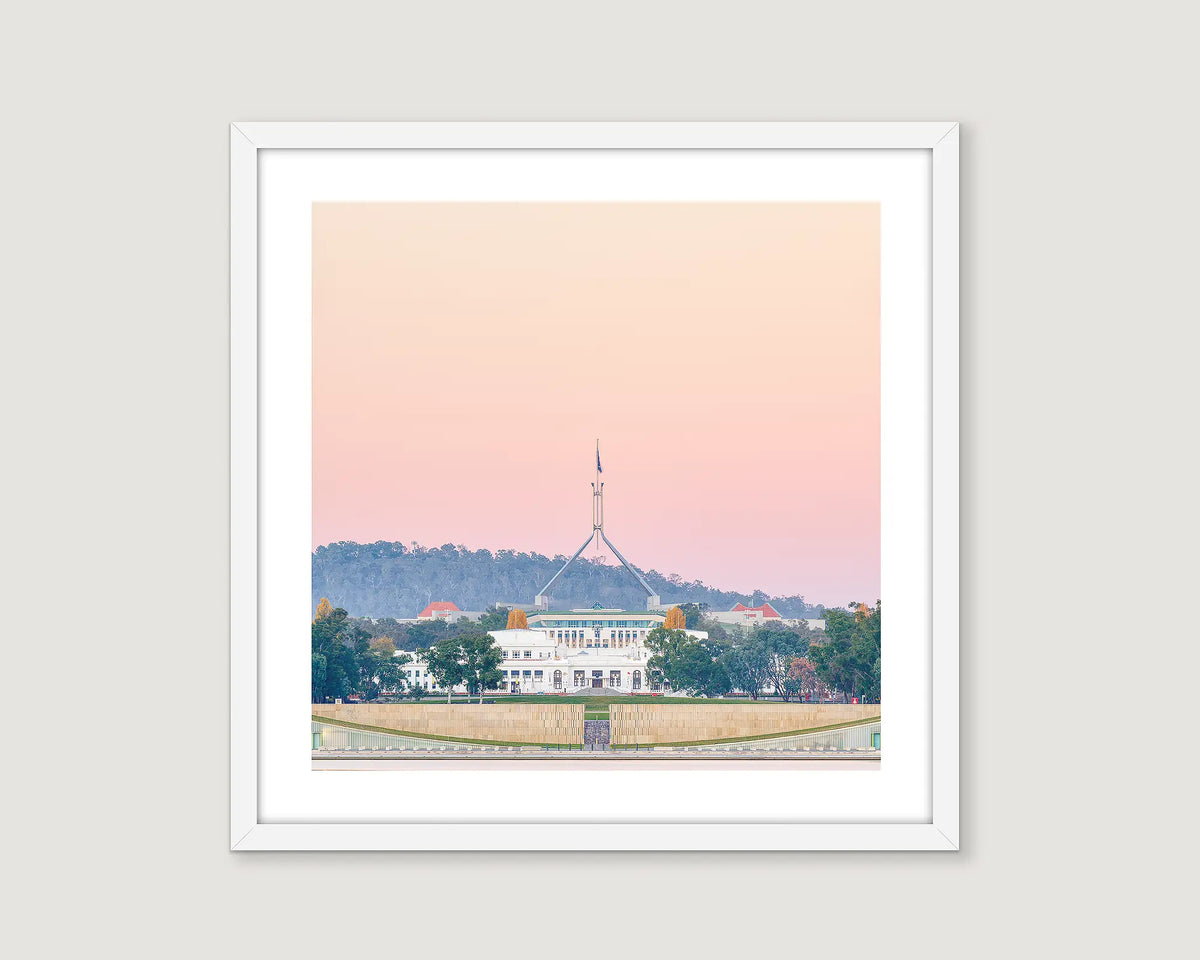 Framed photograph of Old and New Australian Parliament House and a pastel sunset.