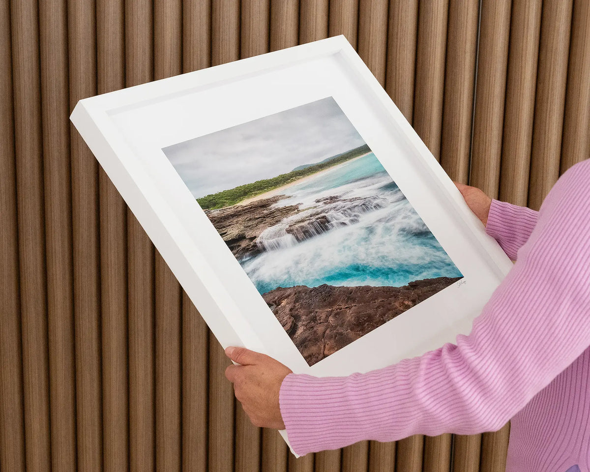 On The Rocks. Wall art print with white frame of South Durras Beach, Eurobodalla, New South Wales, held in hands