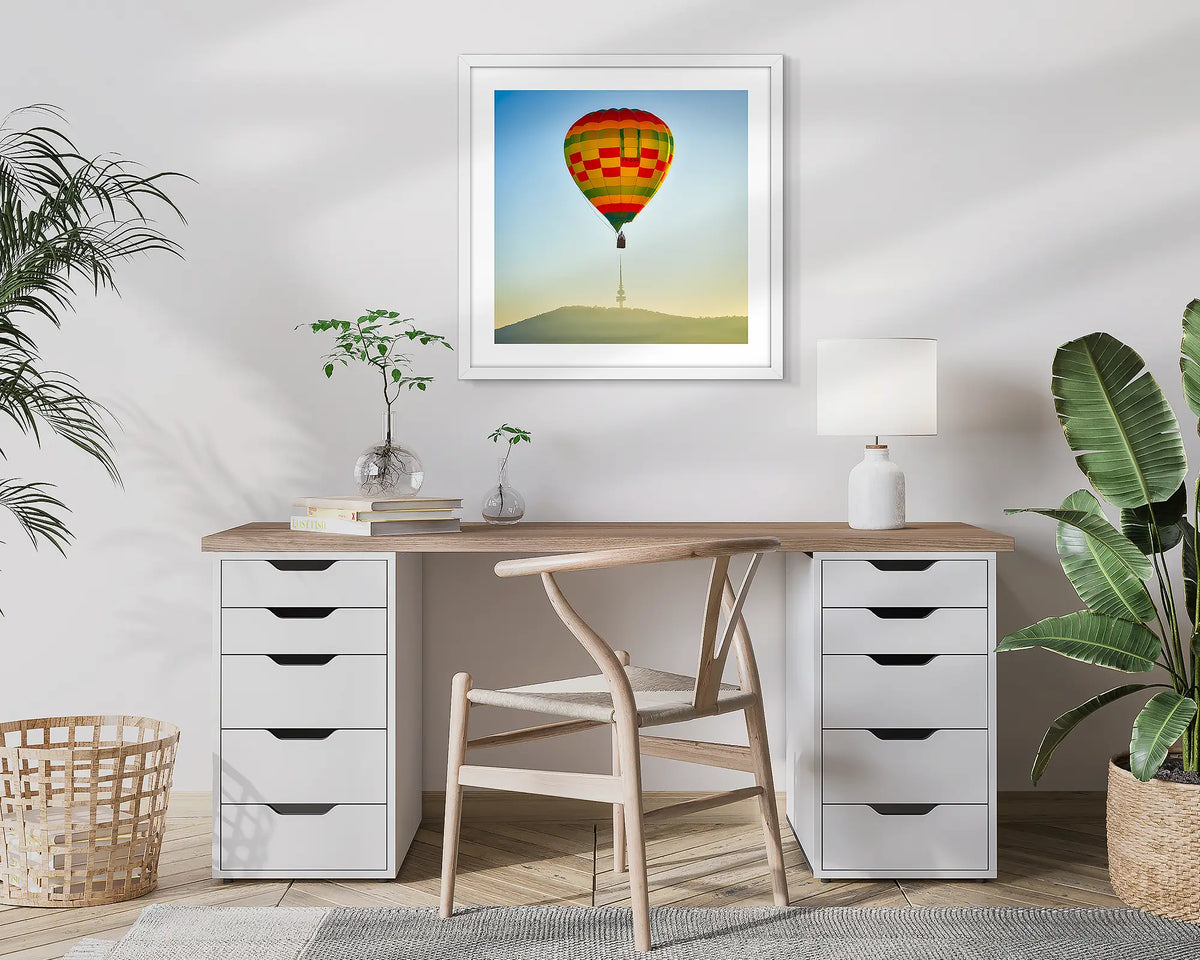 On Top. Canberra wall art print of a hot air balloon and Black Mountain Tower, framed in white and hung in a study. 