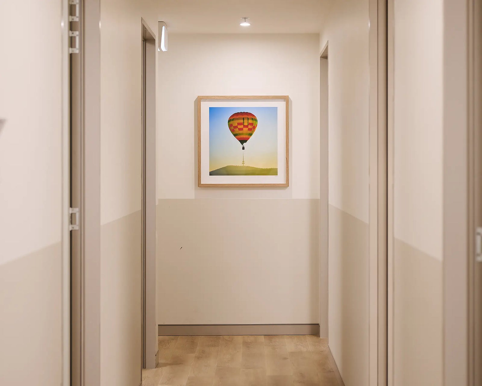 Framed photograph of a hot air balloon above a tower on a mountain.
