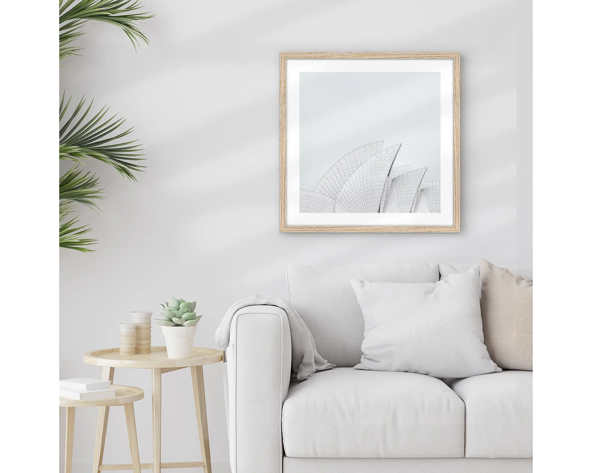 Opera House Curves. Square wall art print featuring sails of the Sydney Opera House, with a timber frame, hung above a couch. 