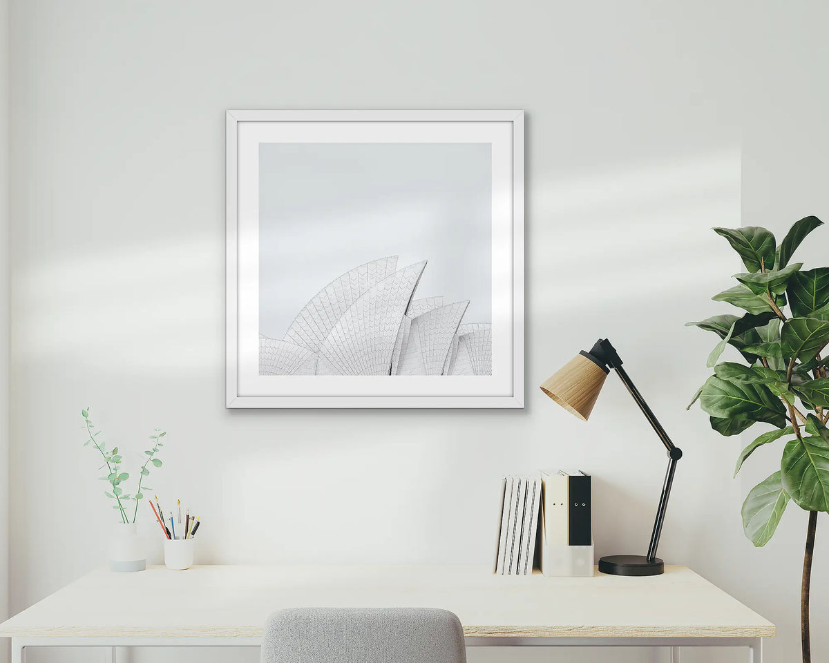 Opera House Curves. Wall art print featuring sails of the Sydney Opera House, with a white frame, hung above a home office desk.