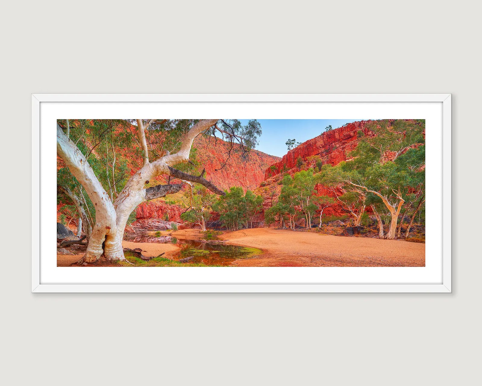 Framed artwork of a scenic landscape photograph of Ormiston Gorge with trees and red rock formations.