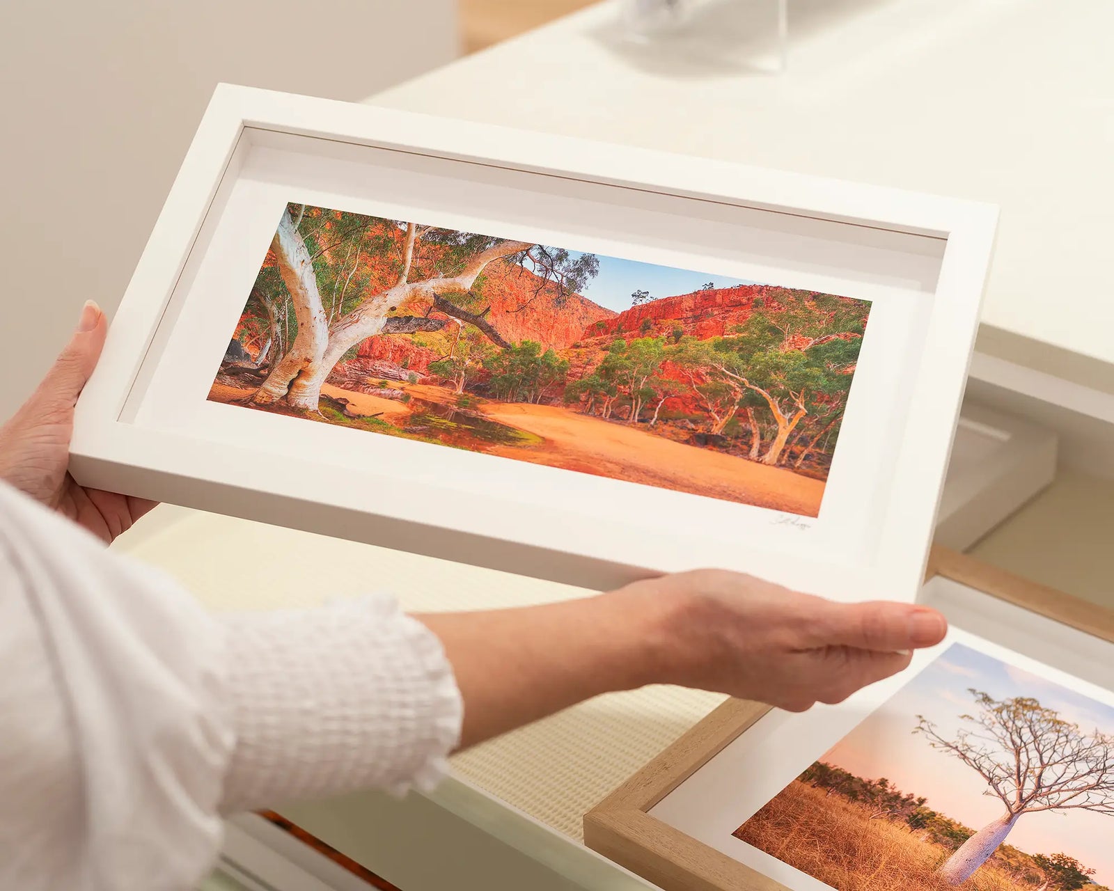 Framed artwork of a scenic landscape photograph of Ormiston Gorge with trees and red rock formations.