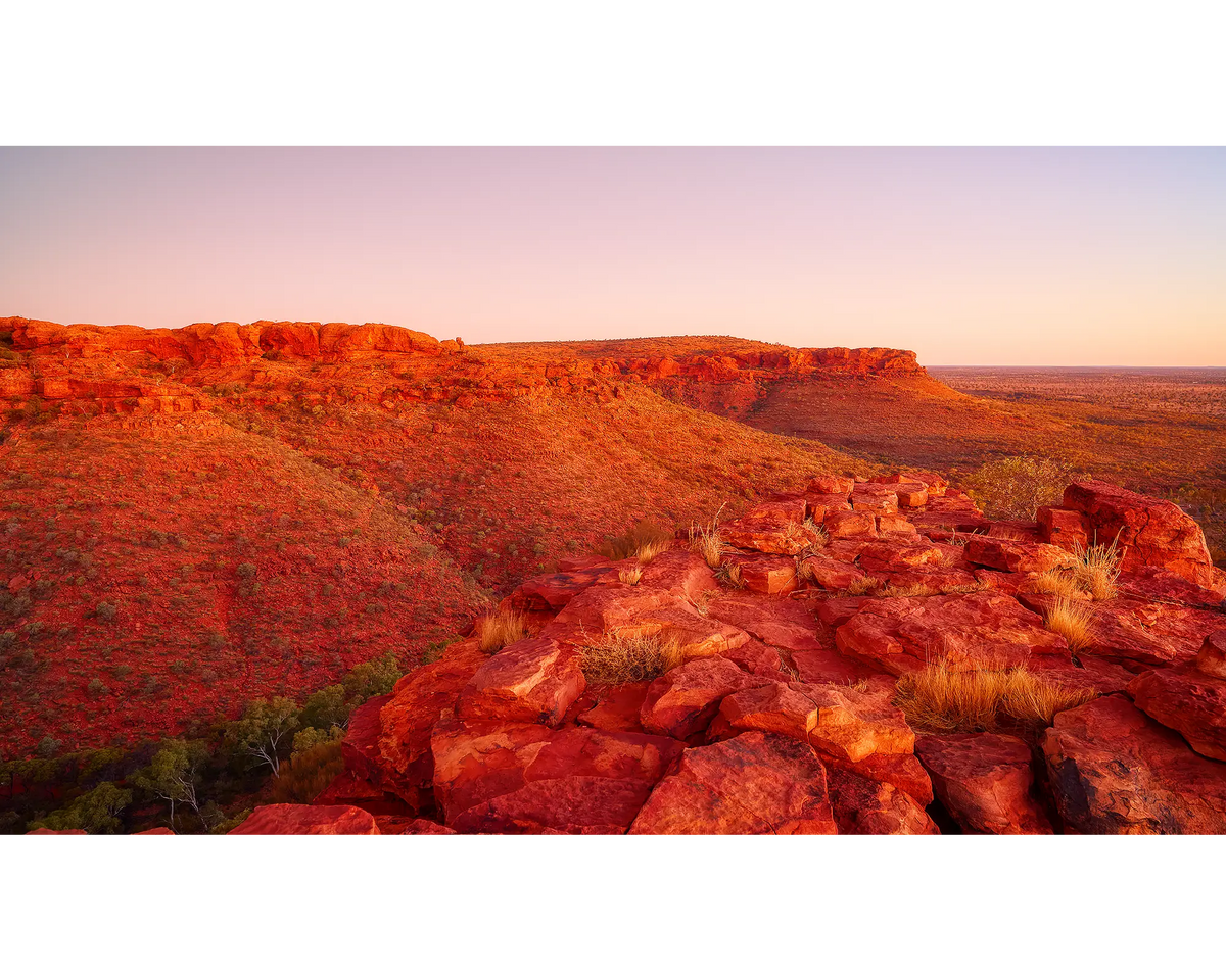 Red rock landscape of Kings Canyon with sunrise over a vast desert area.