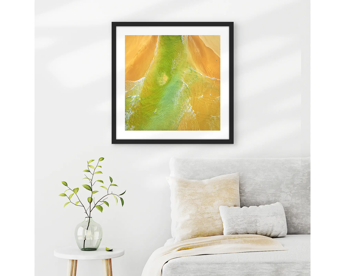Outflow. Abstract wall art print of Durras Lake, framed in a black frame and hung above a bed. 