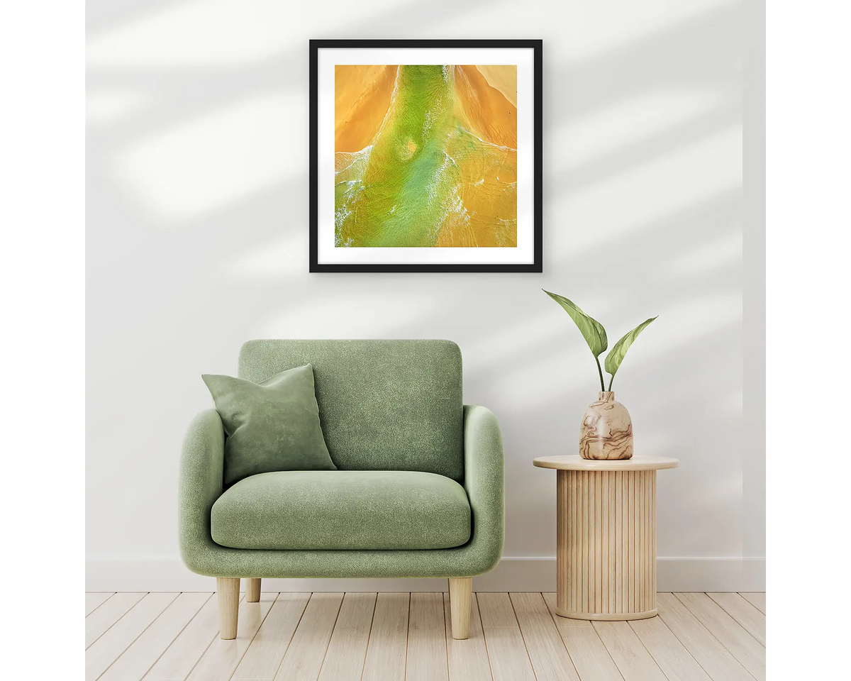 Outflow. Abstract wall art print of Durras Lake, framed in a black frame and hung above a single seat couch. 