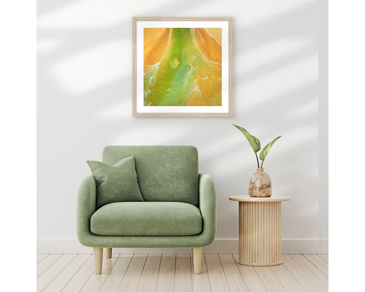 Outflow. Abstract wall art print of Durras Lake, framed in a timber frame and hung above a single seat couch. 