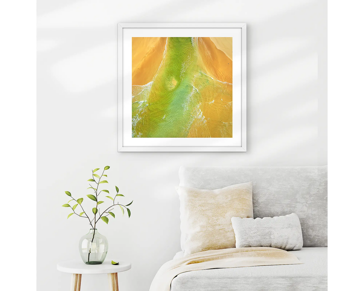 Outflow. Abstract wall art print of Durras Lake, framed in a white frame and hung above a bed. 