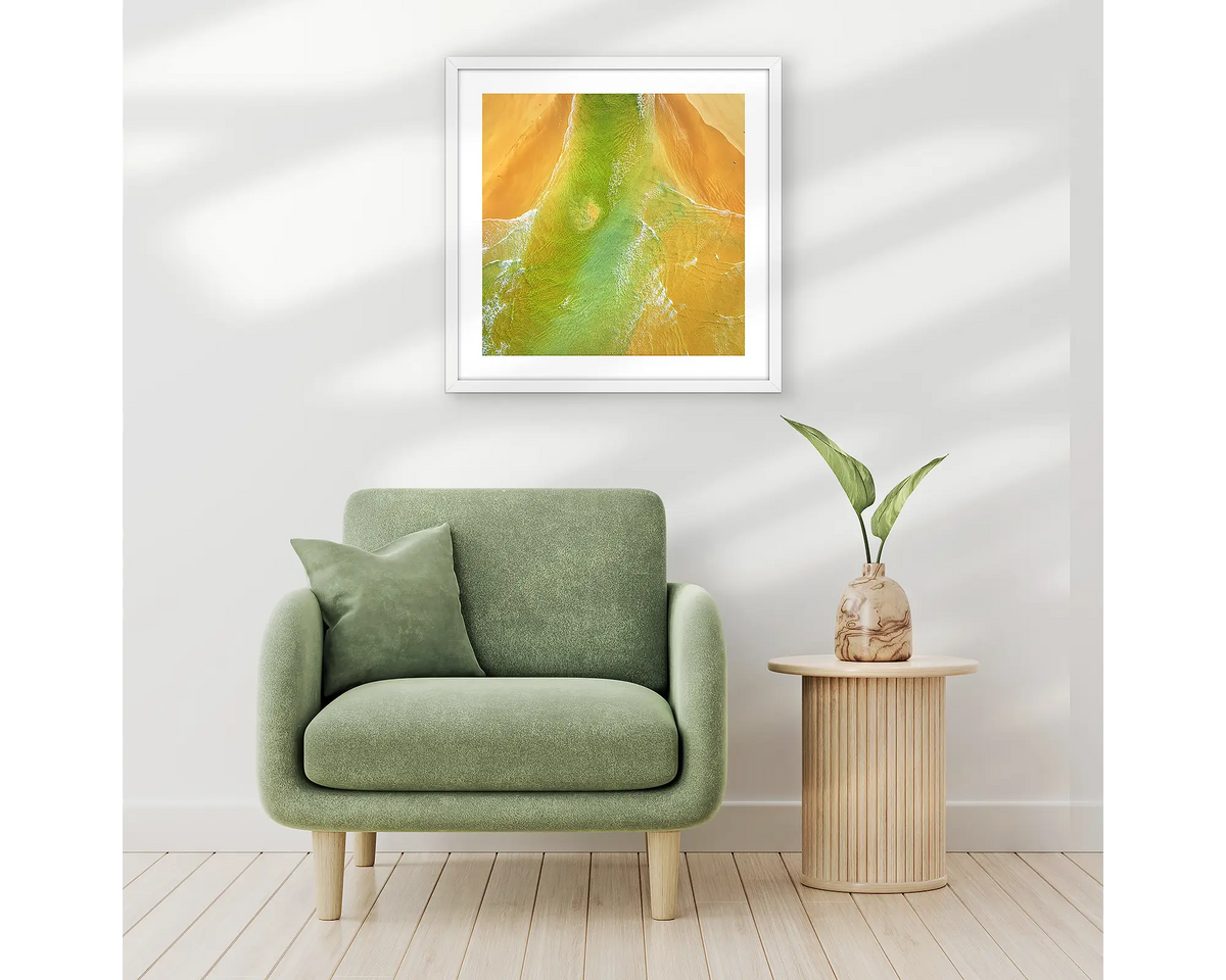 Outflow. Abstract wall art print of Durras Lake, framed in a white frame and hung above a single seat couch. 