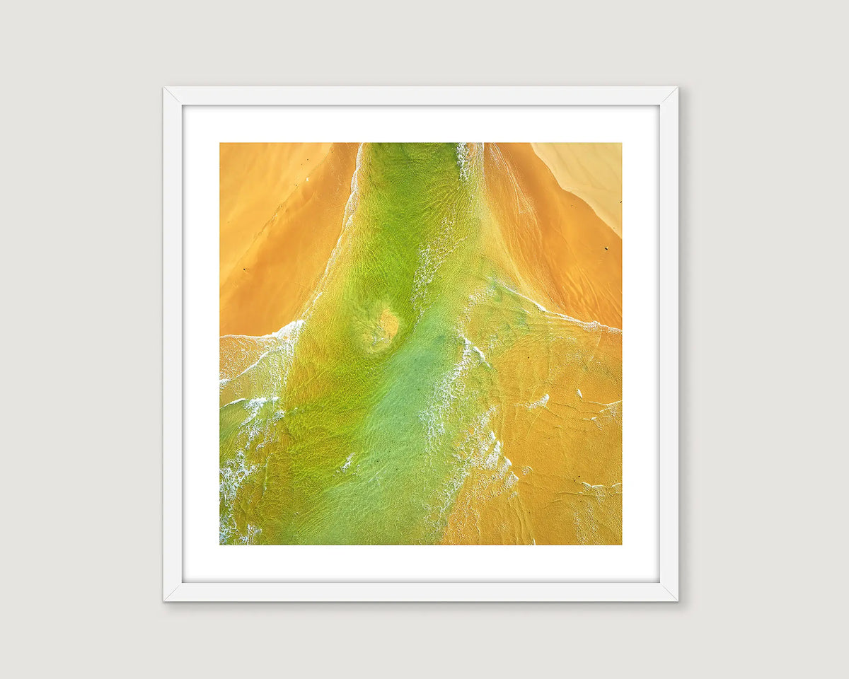 Framed abstract photograph of yellow sand and blue green ocean water.