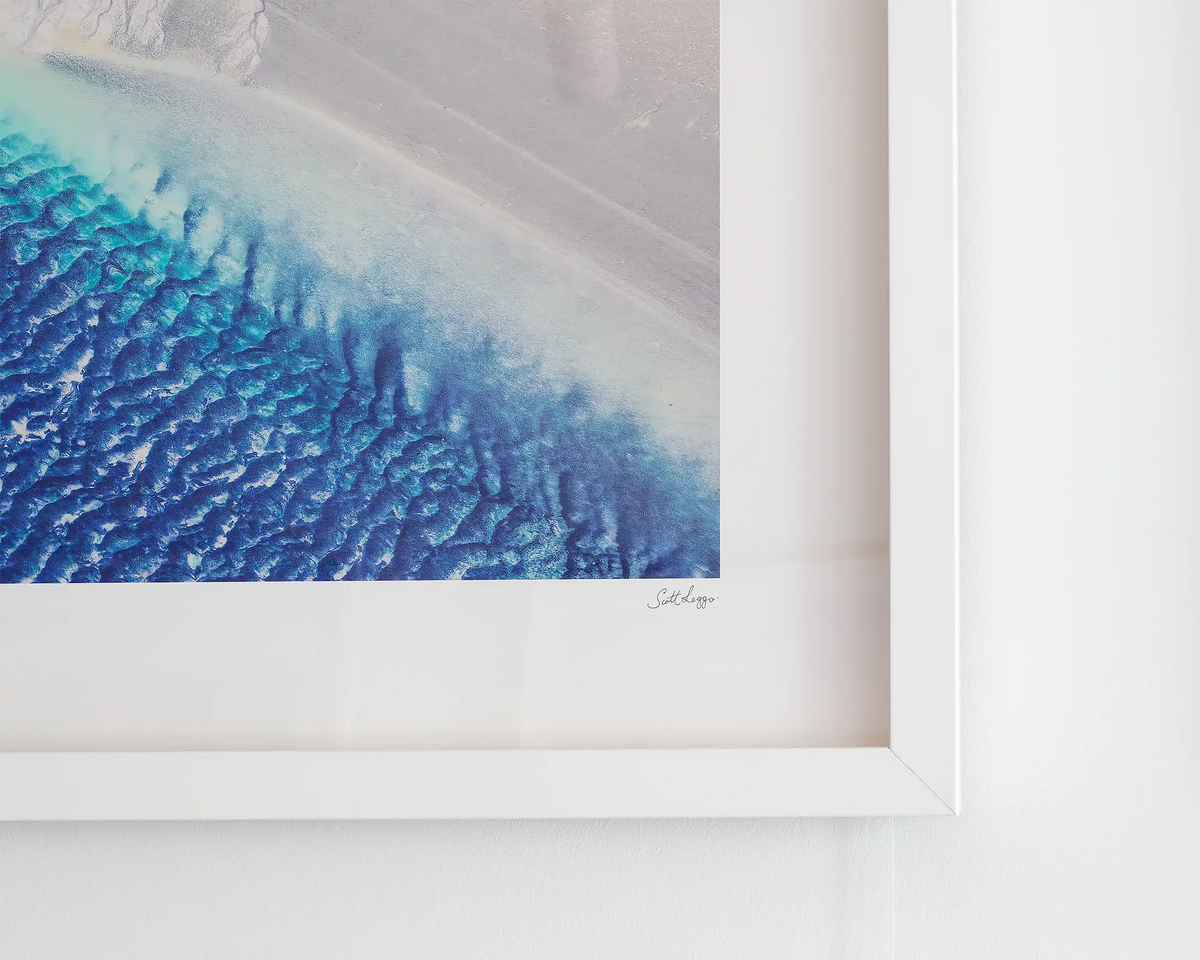Outlet. Aerial landscape photography print framed in white frame hanging on gallery wall.