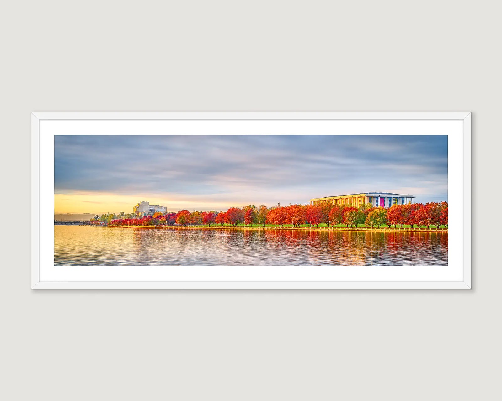 Framed photograph of buildings with red trees and a lake.