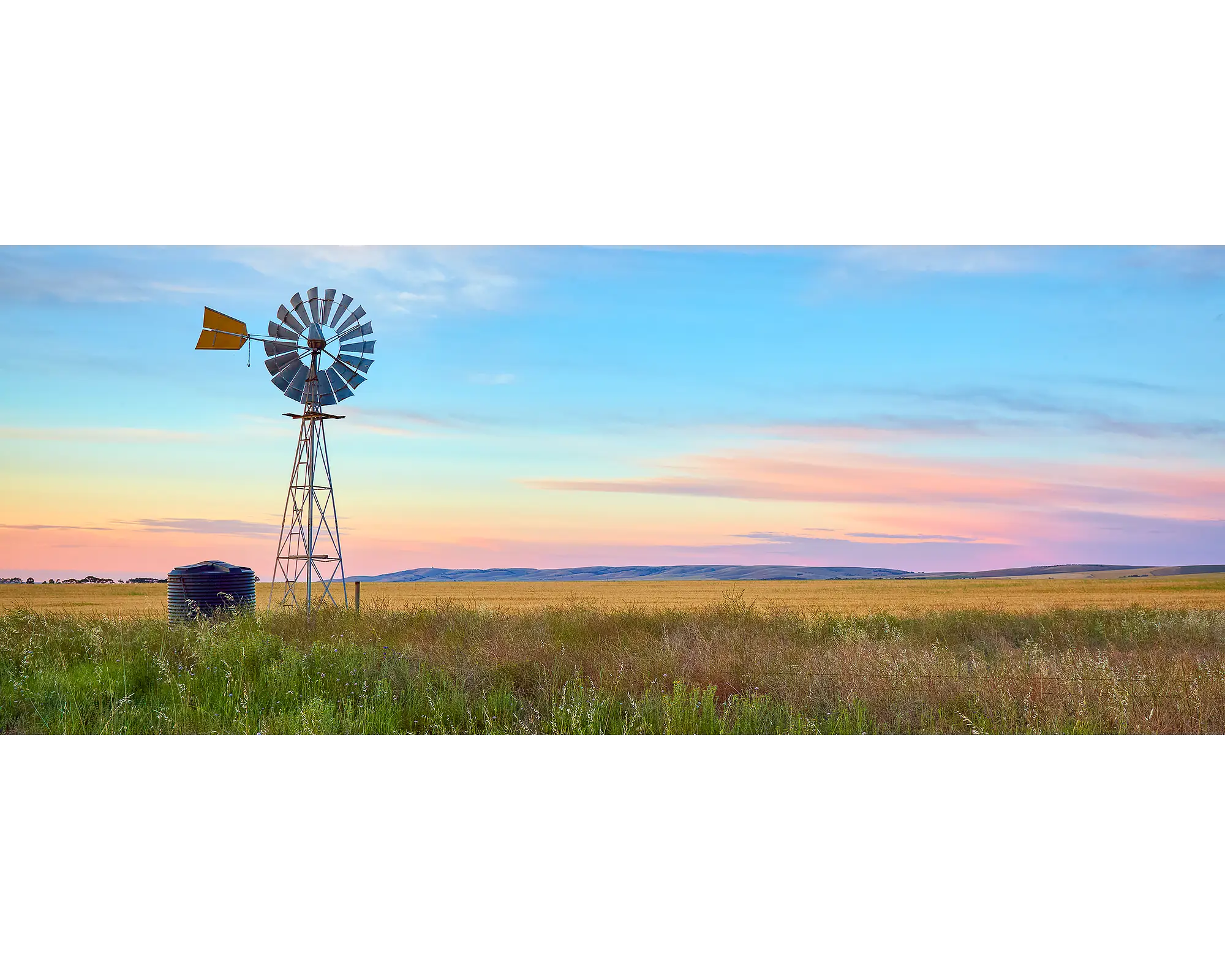 Painted Morning. Windmill on farm with colourful sunrise, South Australia.
