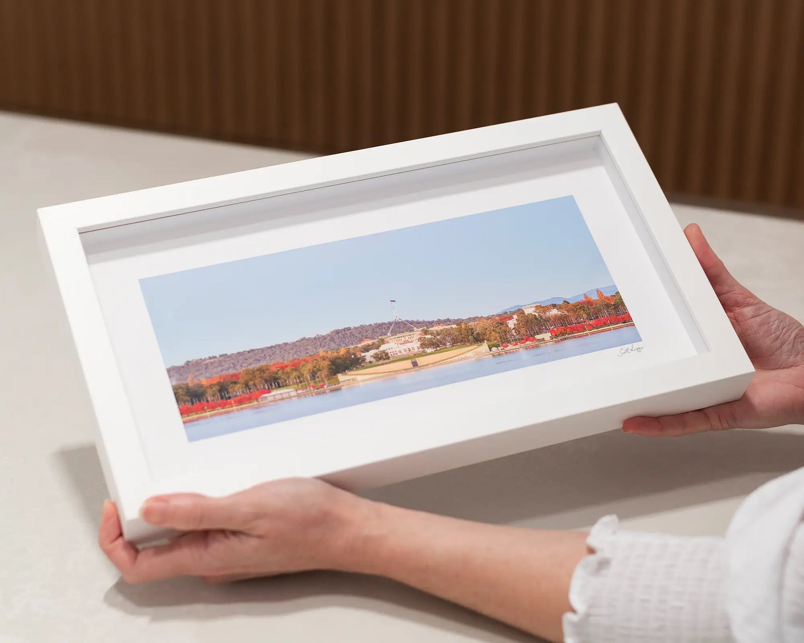 Framed photograph of Australian Parliament House with red trees and a lake.