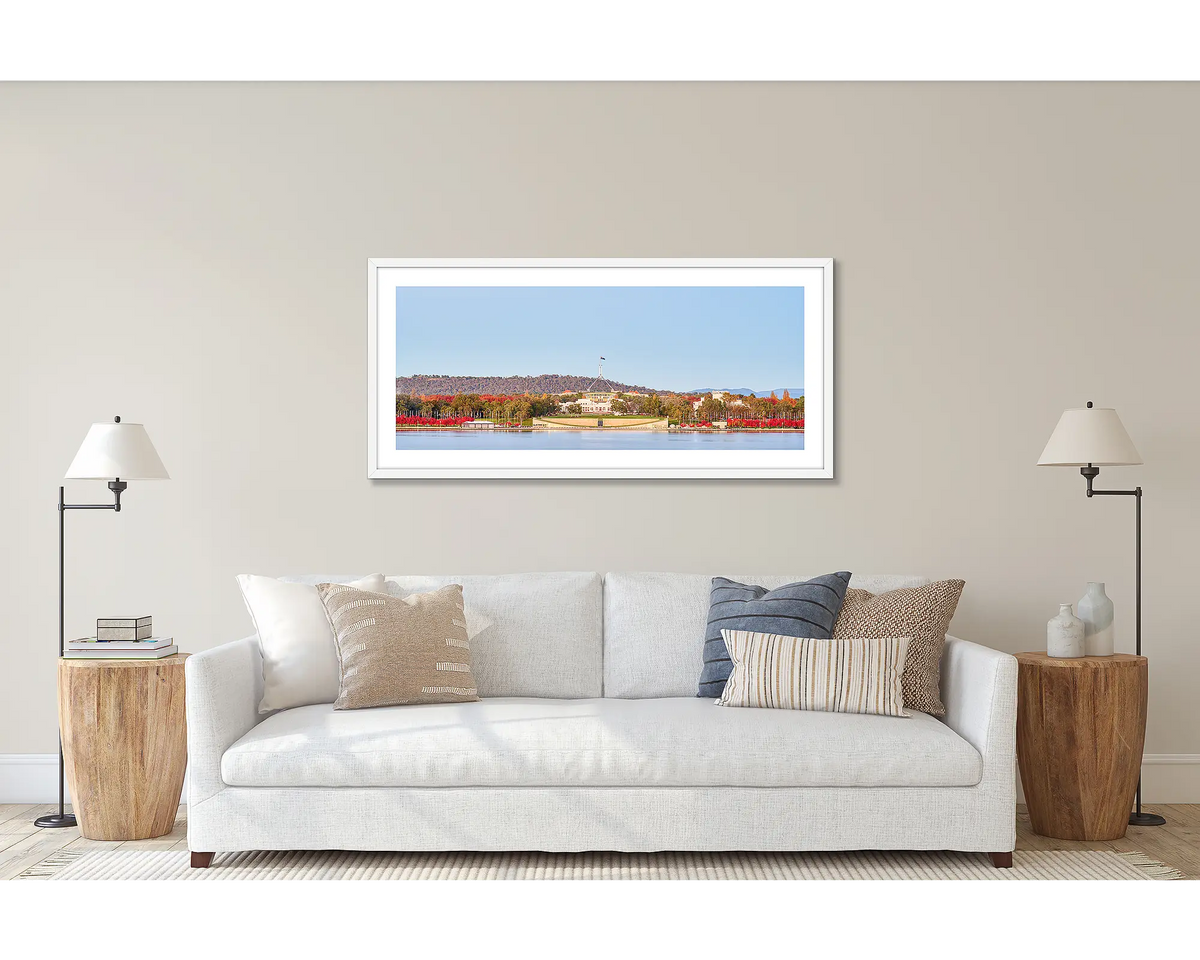 Parliamentary Reds. Wall art print of old and new Parliament House, framed in a white frame and hung above a couch. 
