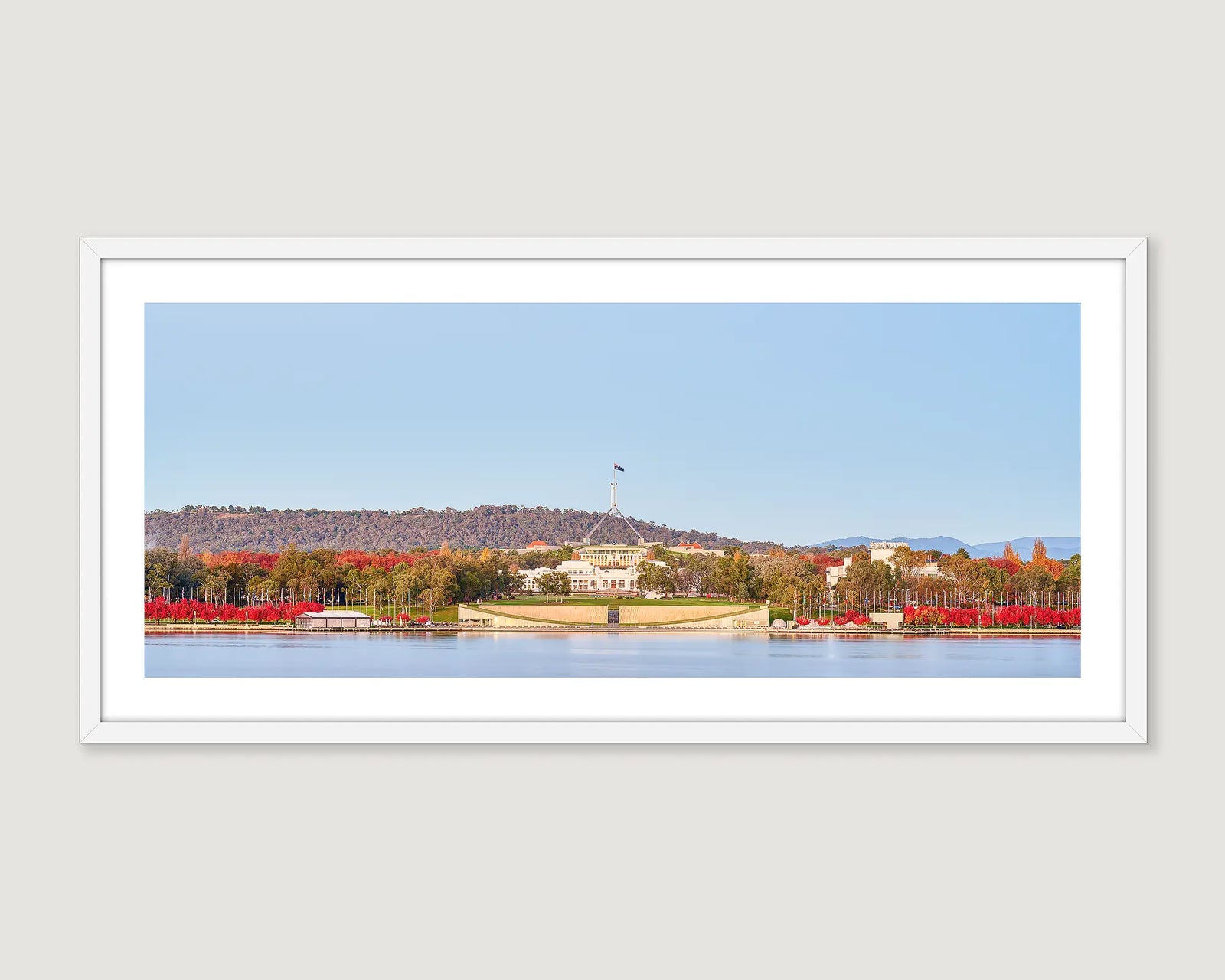 Framed photograph of Australian Parliament House with red trees and a lake.