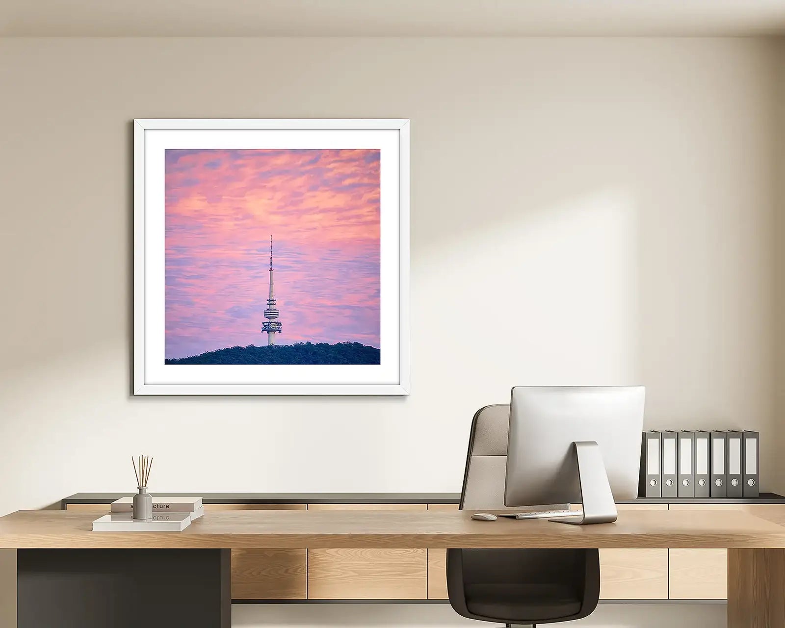 Pink framed wall art hung in light filled office.