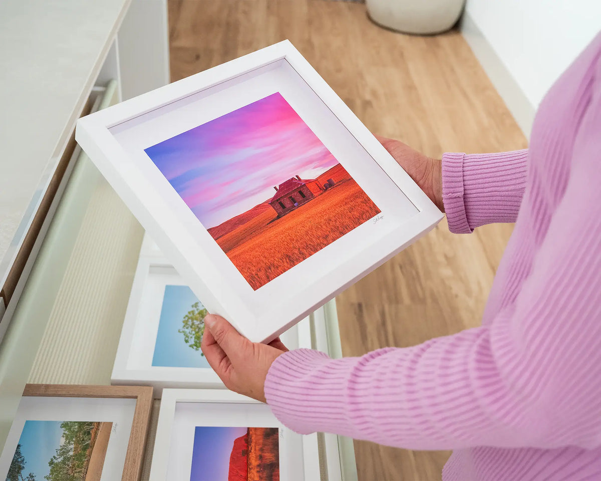 Pioneer. Small print with white frame of an outback homestead, South Australia, held in hands.