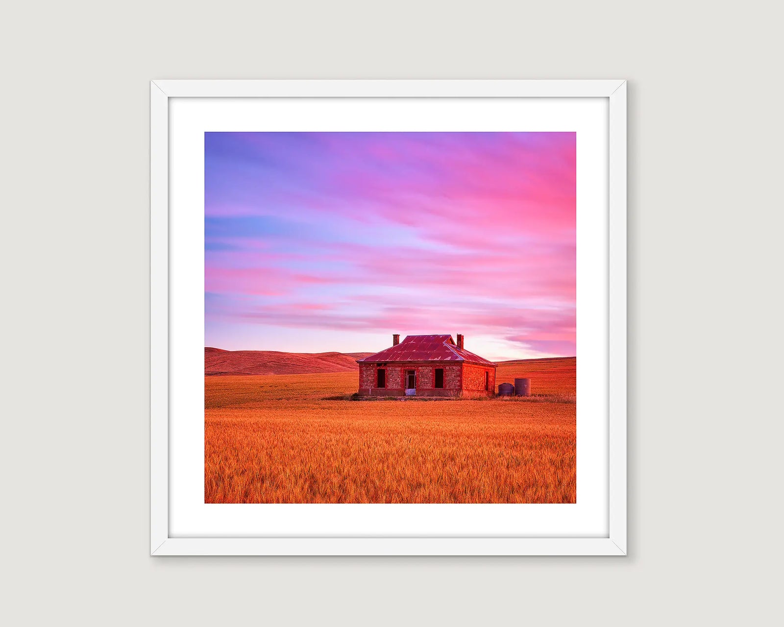 Framed photograph of an abandoned brick and tin roof house in a field with a pink and blue cloudy sky.