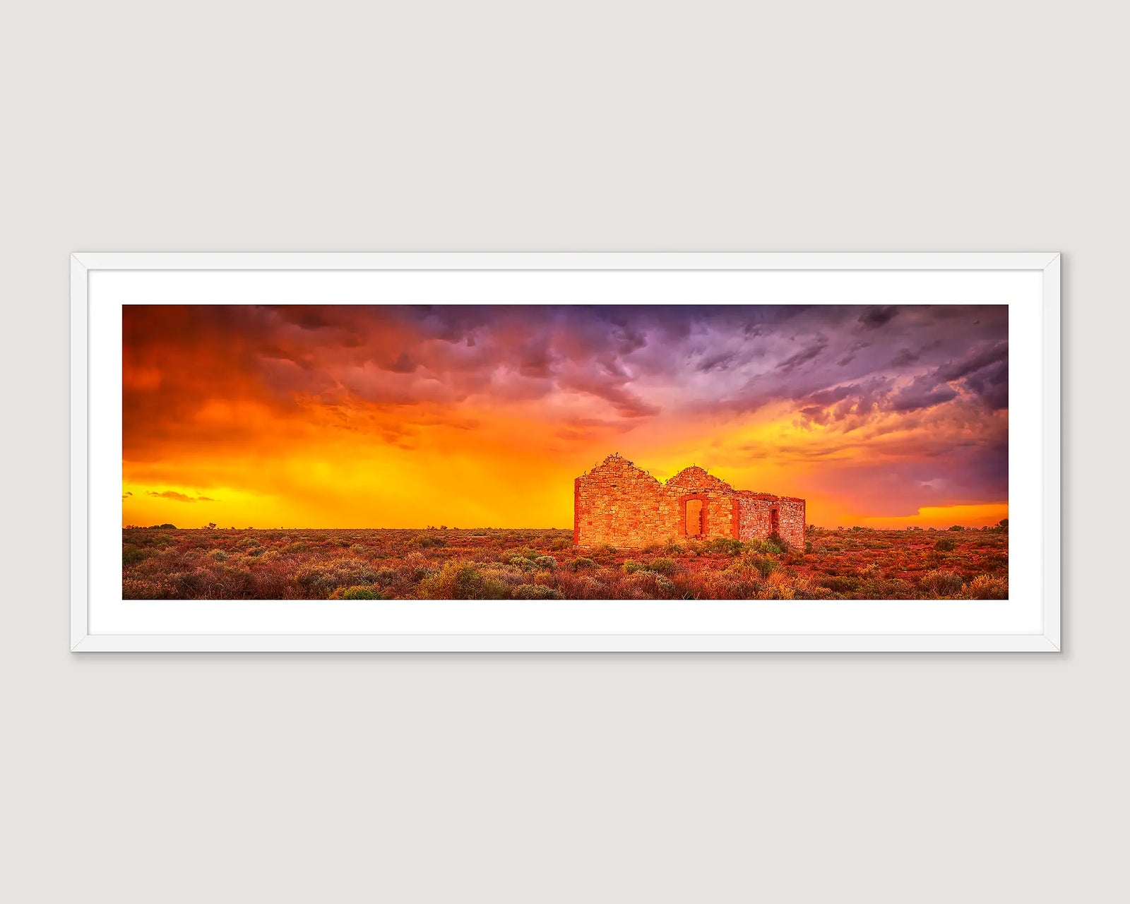 Framed landscape photograph of an abandoned brick home in the outback with a red, purple and yellow sky.