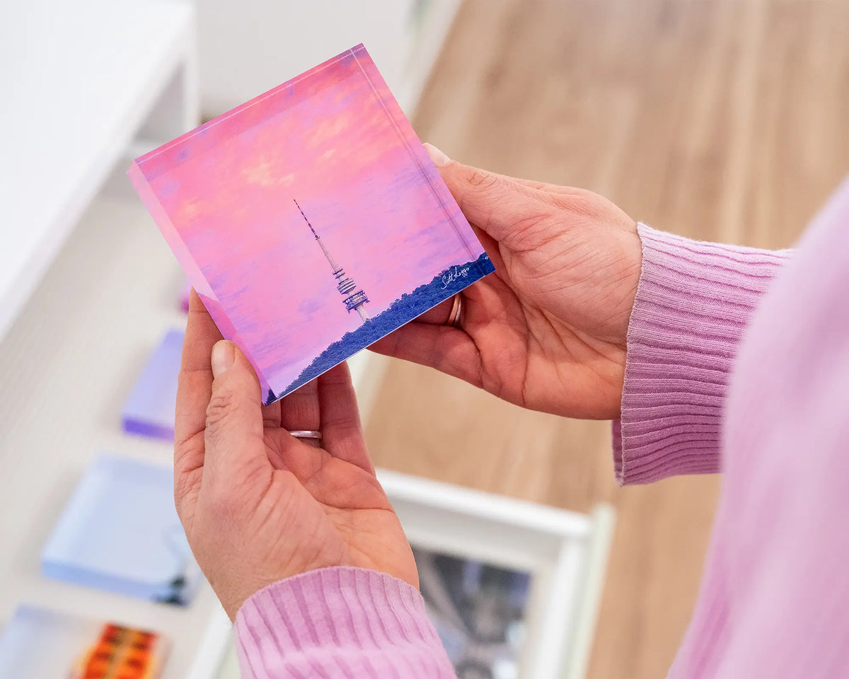 Pointer. Acrylic block of sunrise at Black Mountain Tower, Canberra, held in hands.