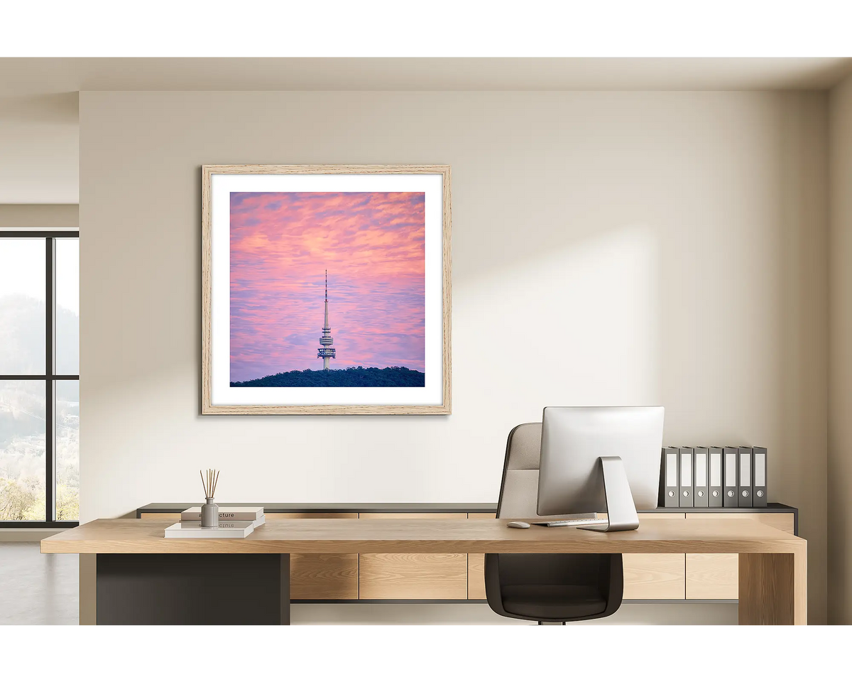 Pointer. Framed wall art print of a Telstra Tower at sunrise, with a timber frame, hung in a light filled office. 