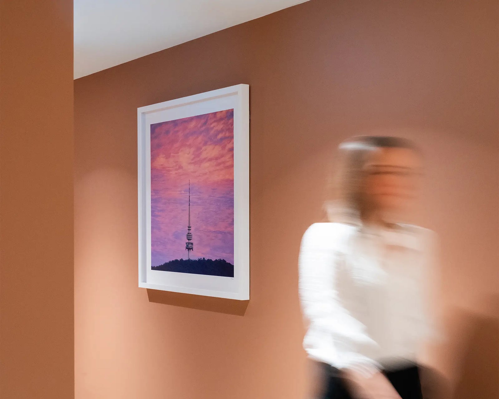Framed photograph of a tower on a mountain with a pink cloudy sky.